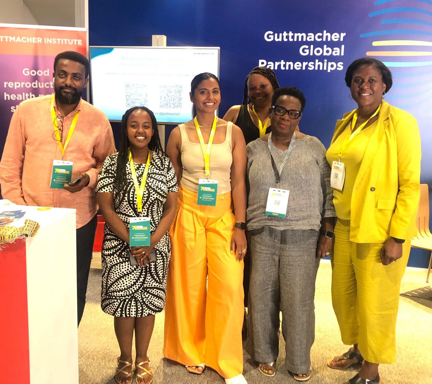 Six persons from TaYa and Guttmacher teams stand in front of Guttmacher booth at 2023 Women Deliver Conference.